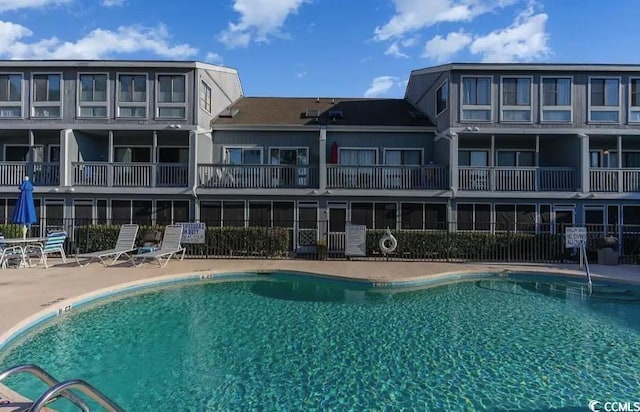 view of pool featuring a water view, a beach view, and a patio