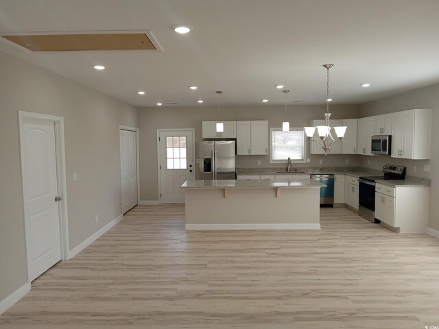 kitchen featuring light wood-style floors, white cabinetry, a kitchen island, and appliances with stainless steel finishes