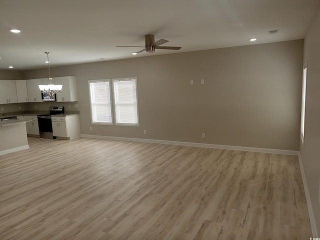 kitchen with baseboards, white cabinets, light wood-style floors, appliances with stainless steel finishes, and open floor plan