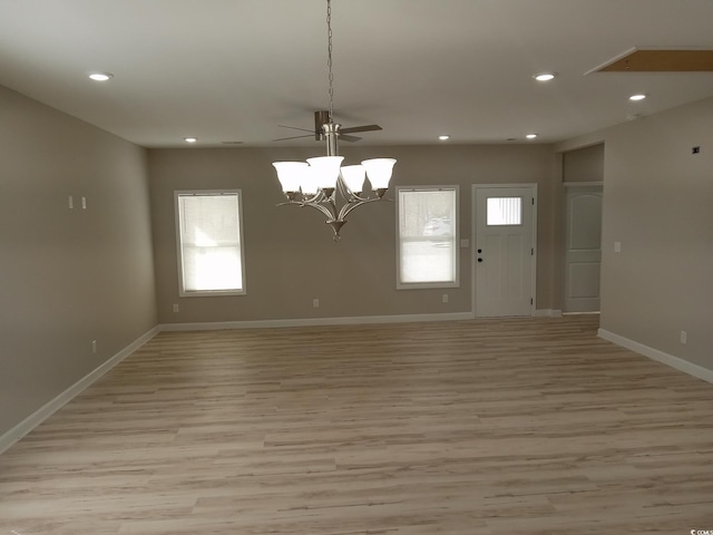 spare room featuring baseboards, ceiling fan with notable chandelier, light wood-style flooring, and recessed lighting