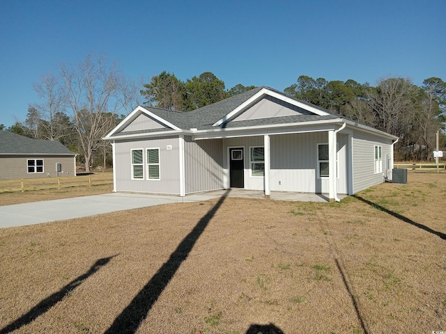 view of front of property with roof with shingles, a front yard, and central air condition unit