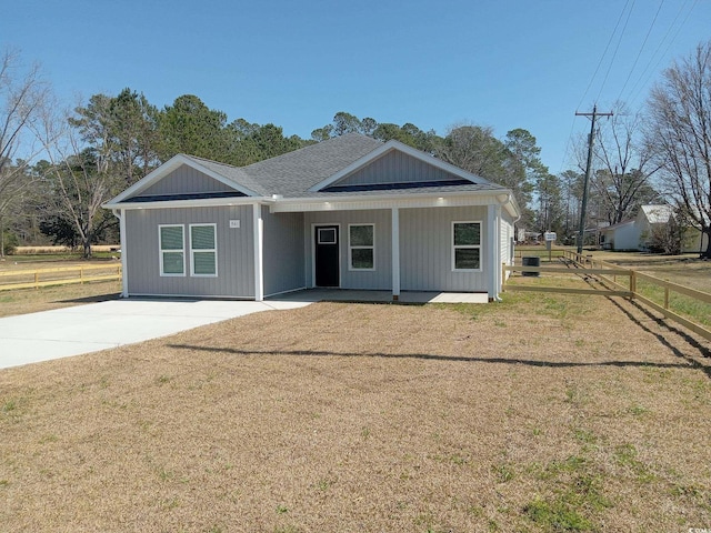 view of front of property with a front lawn, fence, covered porch, and roof with shingles