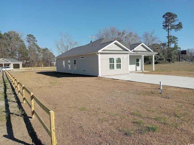 exterior space featuring concrete driveway, fence, and a lawn