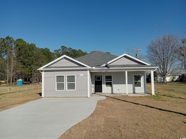 view of front of house with a shingled roof and a front lawn