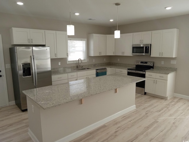 kitchen with appliances with stainless steel finishes, decorative light fixtures, a center island, white cabinetry, and a sink