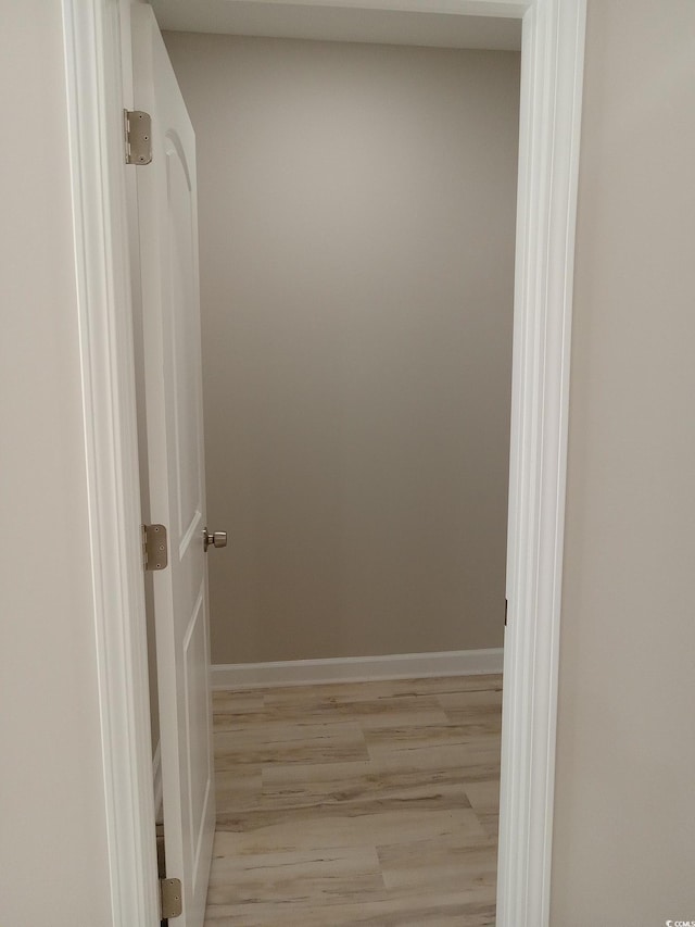 hall featuring light wood-type flooring and baseboards