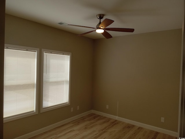 spare room with light wood-style floors, visible vents, baseboards, and a ceiling fan