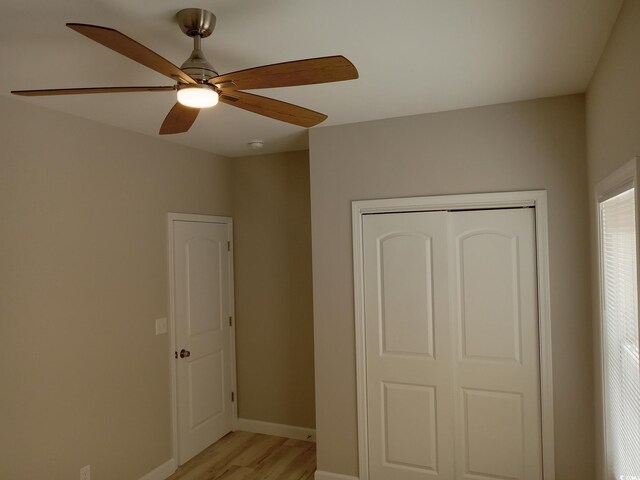 unfurnished bedroom featuring light wood-style floors, a closet, baseboards, and a ceiling fan