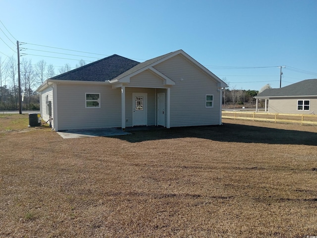 view of front facade with a front yard, roof with shingles, and central AC unit