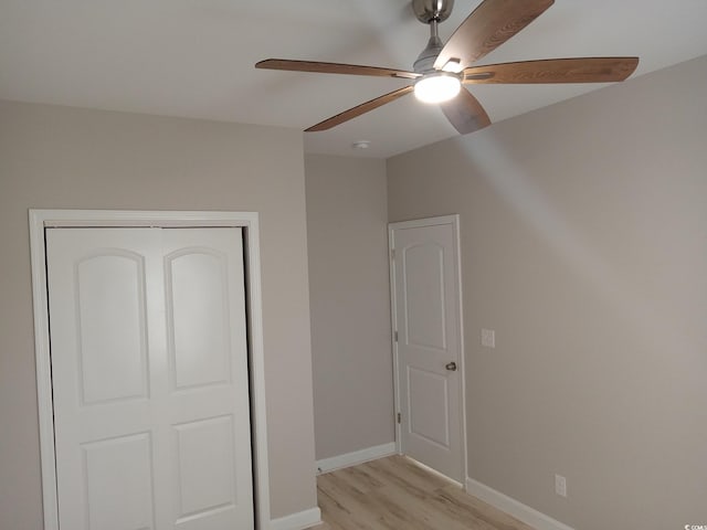 unfurnished bedroom with light wood-type flooring, a closet, ceiling fan, and baseboards