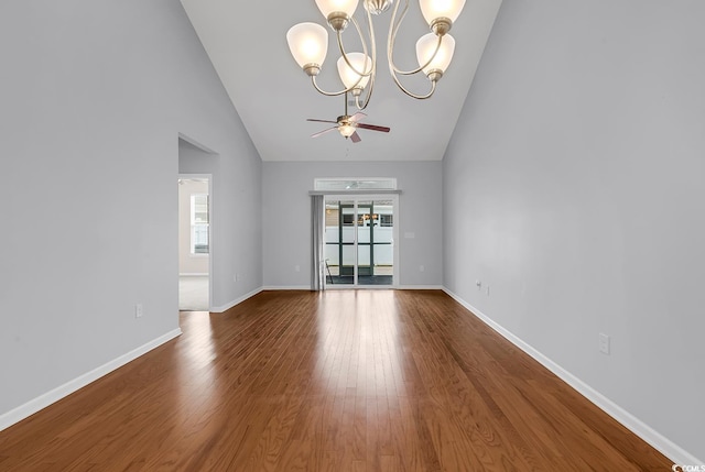 spare room featuring ceiling fan with notable chandelier, hardwood / wood-style flooring, and high vaulted ceiling