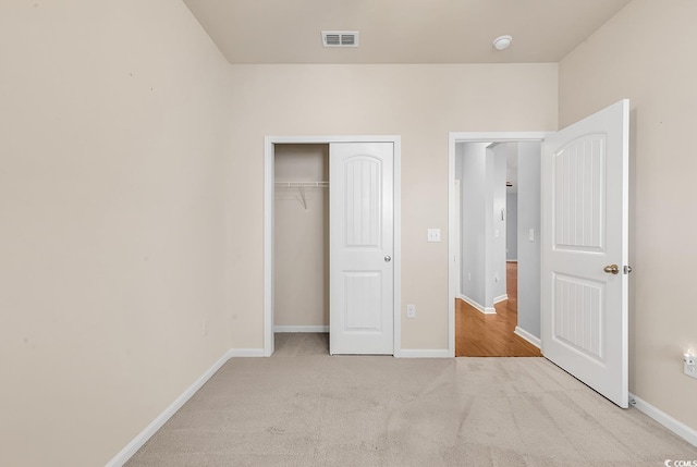 unfurnished bedroom featuring a closet and light colored carpet