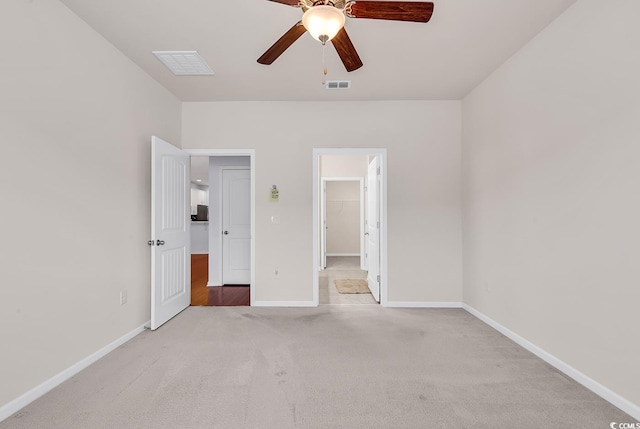 unfurnished bedroom with ceiling fan, a walk in closet, light carpet, and a closet