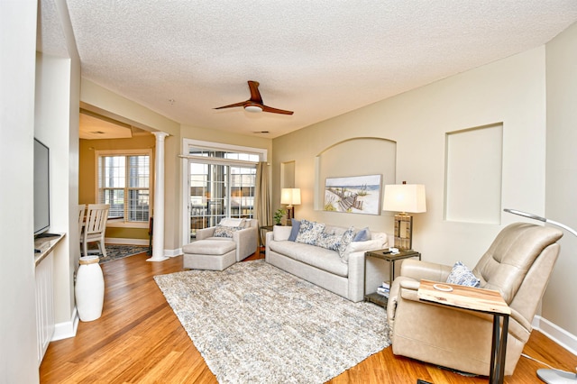 living room featuring hardwood / wood-style floors, ceiling fan, a textured ceiling, and decorative columns