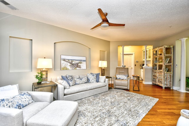 living room featuring ornate columns, ceiling fan, hardwood / wood-style floors, and a textured ceiling