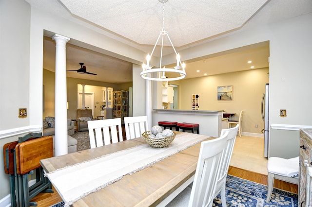 dining space featuring a textured ceiling, ceiling fan with notable chandelier, light hardwood / wood-style flooring, and crown molding