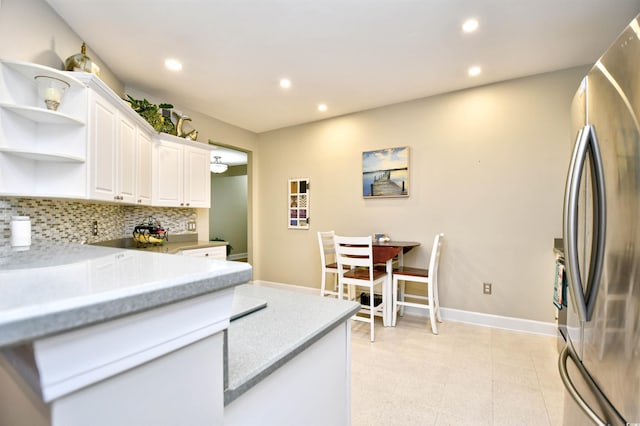 kitchen with tasteful backsplash, stainless steel fridge, and white cabinets