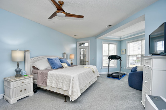 bedroom with a textured ceiling, light colored carpet, and ceiling fan