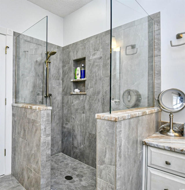 bathroom with a tile shower and vanity