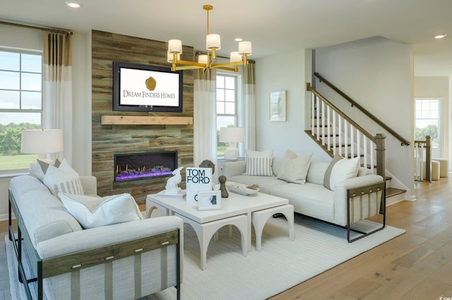 living room with a tile fireplace, wooden walls, wood-type flooring, and a notable chandelier