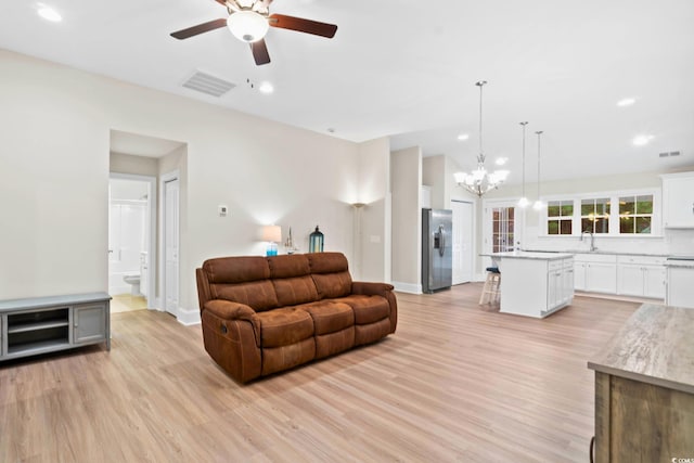 living room with ceiling fan with notable chandelier, light hardwood / wood-style floors, and sink