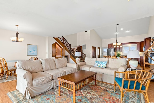 living room featuring a chandelier, vaulted ceiling, and light wood-type flooring