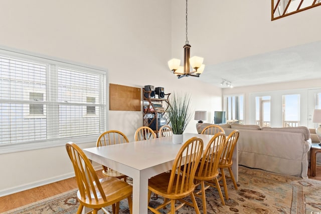 dining area featuring a wealth of natural light, wood-type flooring, and a notable chandelier