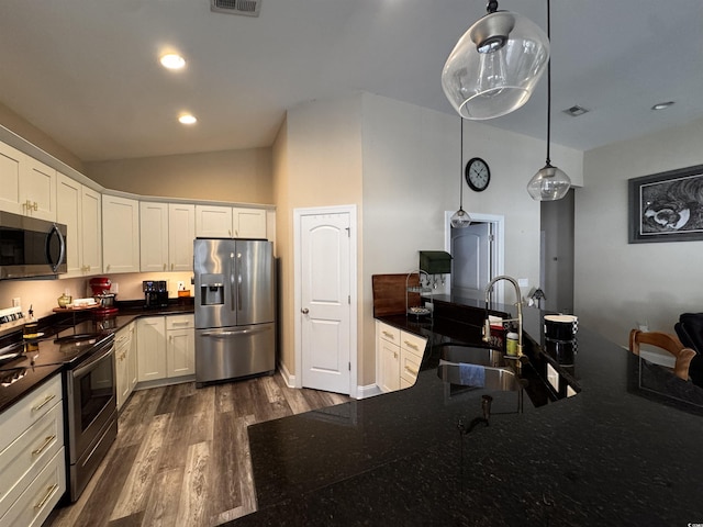 kitchen featuring appliances with stainless steel finishes, dark countertops, white cabinets, and hanging light fixtures