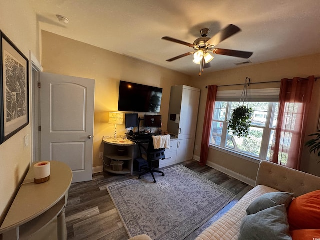 home office with dark wood-style floors, ceiling fan, visible vents, and baseboards