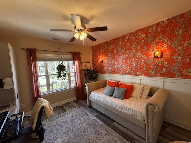 bedroom featuring a wainscoted wall, dark wood finished floors, visible vents, and wallpapered walls