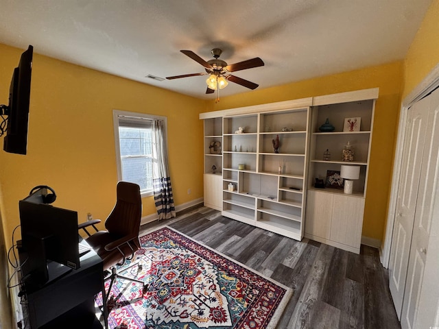 office space featuring a ceiling fan, visible vents, dark wood finished floors, and baseboards