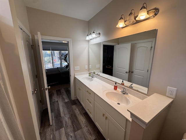 ensuite bathroom featuring double vanity, a sink, ensuite bathroom, and wood finished floors