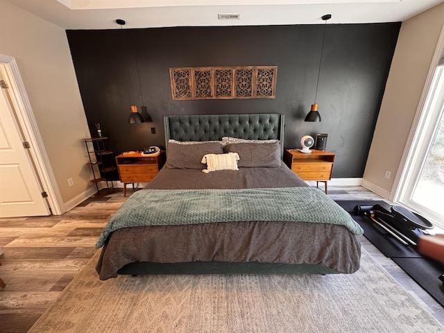 bedroom with visible vents, baseboards, and wood finished floors