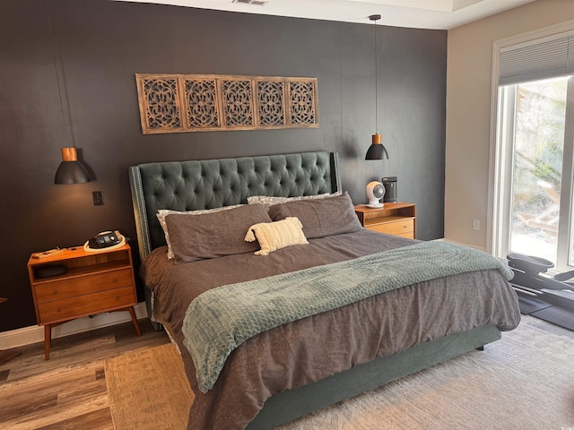 bedroom with access to outside, visible vents, and wood finished floors