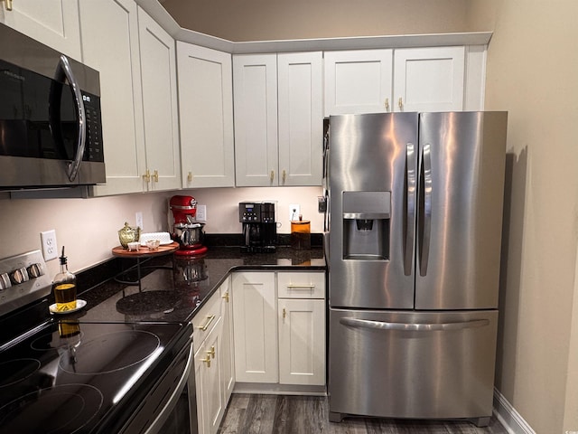 kitchen featuring stainless steel appliances, dark wood-type flooring, white cabinetry, dark stone counters, and baseboards