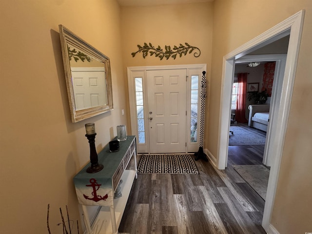 foyer entrance with dark wood-style flooring and baseboards