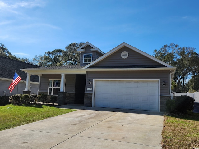 craftsman house with stone siding, a front lawn, an attached garage, and driveway