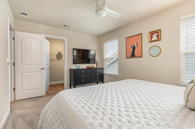 bedroom with light carpet, a closet, a spacious closet, and ceiling fan