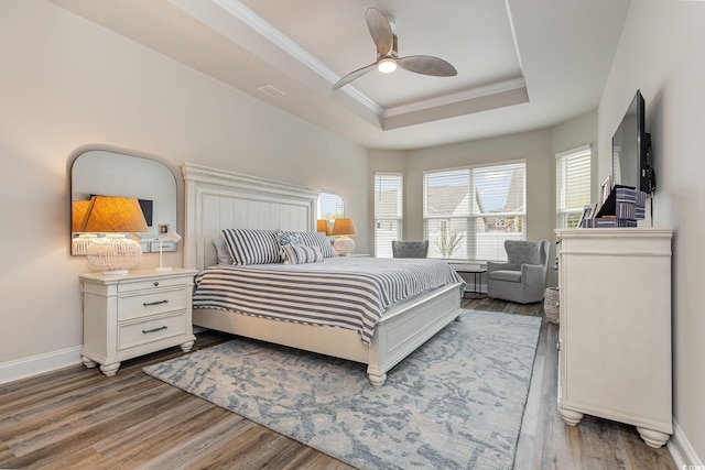 bedroom with hardwood / wood-style floors, a tray ceiling, ceiling fan, and ornamental molding