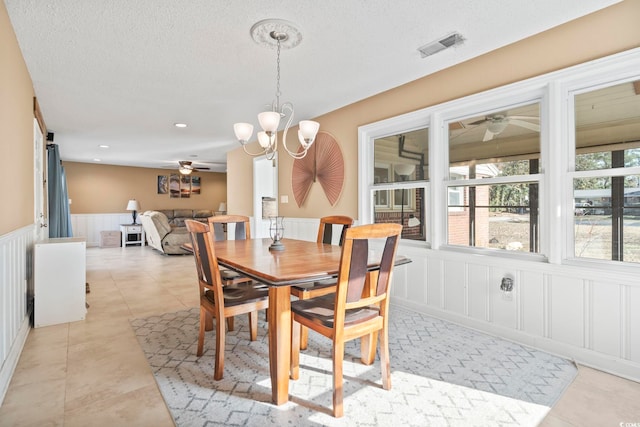 tiled dining area with a textured ceiling and ceiling fan with notable chandelier