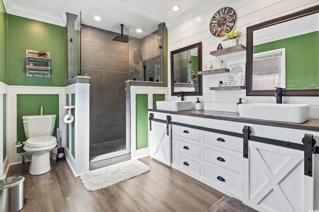 bathroom with hardwood / wood-style flooring, vanity, toilet, and a tile shower