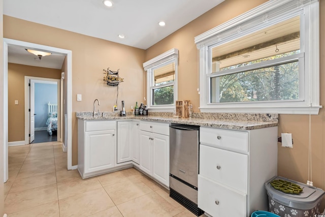 kitchen featuring light stone counters, sink, white cabinets, and light tile patterned floors