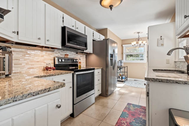 kitchen featuring an inviting chandelier, sink, appliances with stainless steel finishes, light tile patterned flooring, and white cabinetry