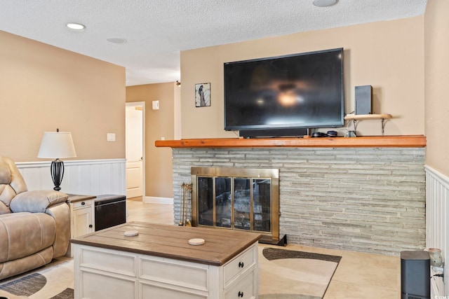 living room featuring a fireplace, light tile patterned floors, and a textured ceiling