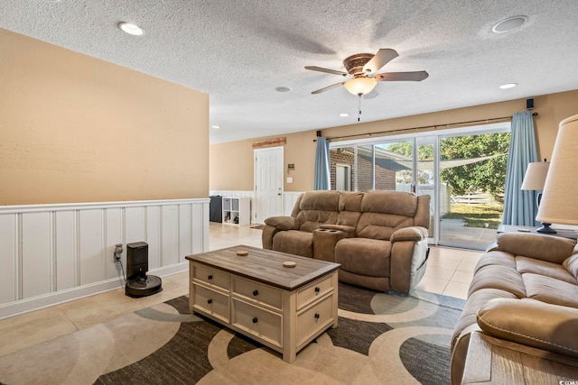 living room with ceiling fan, light tile patterned floors, and a textured ceiling