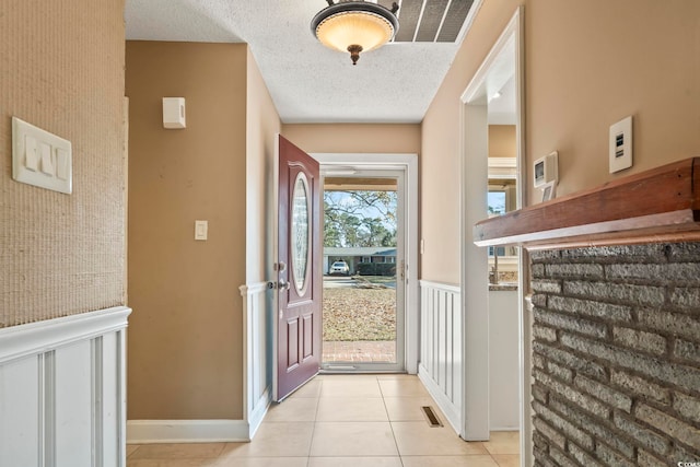 foyer featuring light tile patterned floors and a textured ceiling