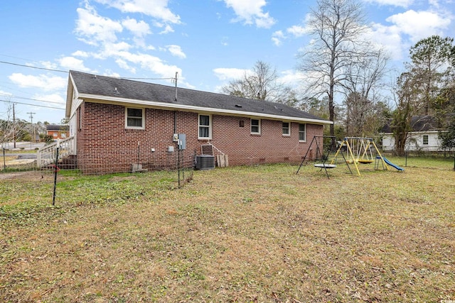 rear view of house with a lawn, central AC unit, and a playground