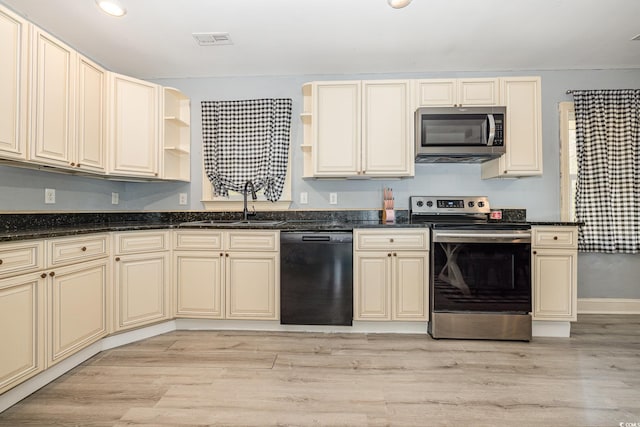 kitchen with cream cabinets, stainless steel appliances, and light wood-type flooring