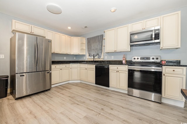 kitchen featuring cream cabinetry, stainless steel appliances, light hardwood / wood-style flooring, and sink