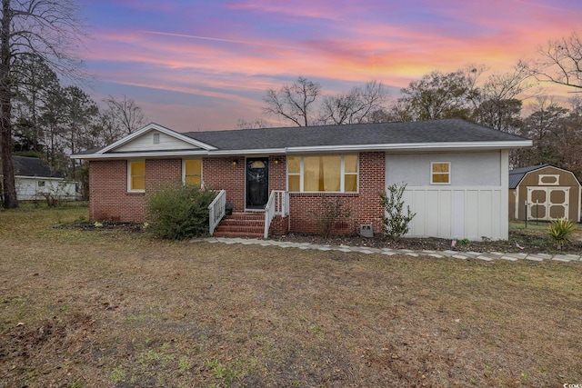 single story home featuring a lawn and a storage unit